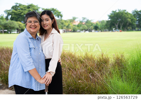 Portrait of Asian mother and Grown daughter showing love and hug and happy moment. Happy Mother Day, Asian careful caregiver or nurse hold the patient hand and encourage the patient in a garden 126563729