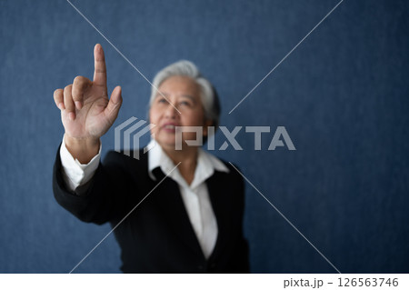 Portrait of middle aged business woman standing isolated on blue background and posing finger pointing and touching, looking at the camera with smile, Successful businesswoman, ceo, director, manager 126563746