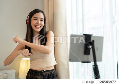 Asian women and beautiful bloggers wear headphones dancing videos by smartphone cameras. Creator vlogger talent dancing enjoys hobby content recording show video sharing on social media. 126563977