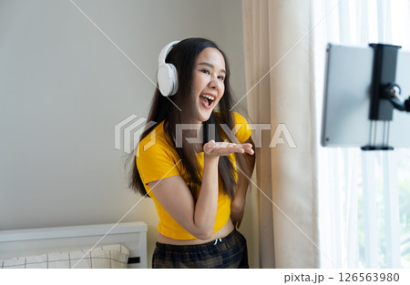 Asian women and beautiful bloggers wear headphones dancing videos by smartphone cameras. Creator vlogger talent dancing enjoys hobby content recording show video sharing on social media. 126563980
