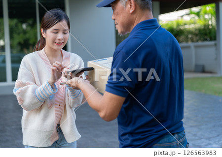Cheerful Asian women receive product box from delivery service and pays by scanning QR code from smartphone, home deliveries, a convenient shopping experience, and trustworthy doorstep service concept Cheerful Asian women receive product box from delivery service and pays by scanning QR code from smartphone, home deliveries, a convenient shopping experience, and trustworthy doorstep service concept 126563983
