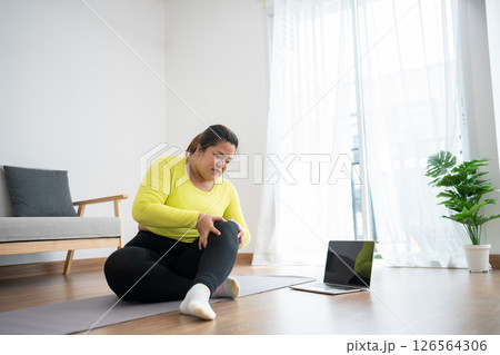 Unhappy plus size woman sitting on the floor, having knee pain during exercise, unable to exercise because of sports injury, feeling pain. Exercising properly concept, health care. weight loss 126564306