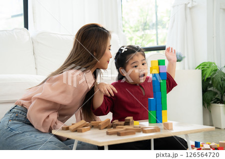 Cherry young mother plays colorful toy block with her Down syndrome daughter,  colorful wooden toys can increase skills and learning to increase the development, special education, Knowing slowly 126564720