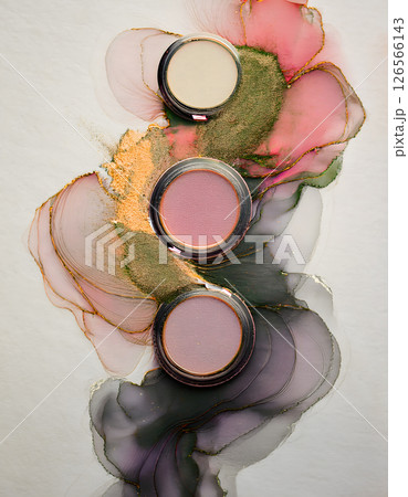 Vibrant makeup pans rest on a swirling canvas of abstract color and metallic inks, creating a visually stunning, artistic composition 126566143