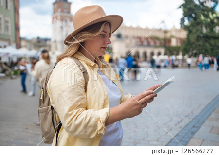Woman in a city square holding a map, exploring the surroundings Woman in a city square holding a map, exploring the surroundings 126566277