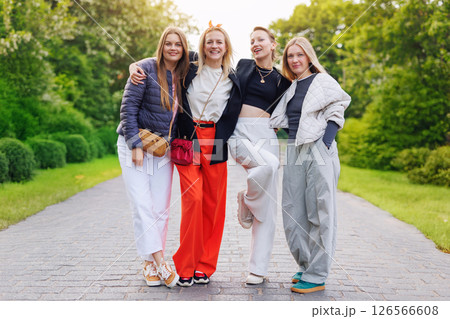 Portrait four cheerful young adult women friend walk street park  european german town city enjoy have fun laughing sunny day together. Female persons friendship celebration party event weekend 126566608