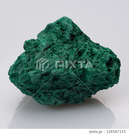 A striking specimen of vibrant green malachite, a hydrated copper carbonate mineral, presents a dense, botryoidal texture its rough, uneven surface reflects light A striking specimen of vibrant green malachite, a hydrated copper carbonate mineral, presents a dense, botryoidal texture its rough, uneven surface reflects light 126567155