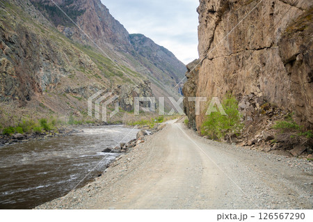 Gravel road running along Chulyshman river in mountain valley Altai Russia Remote travel route through scenic wilderness 126567290