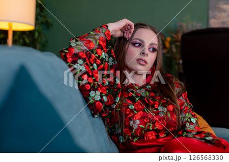A Stylish Woman Wearing a Colorful Floral Outfit is Relaxing at Home in a Cozy Environment A Stylish Woman Wearing a Colorful Floral Outfit is Relaxing at Home in a Cozy Environment 126568330