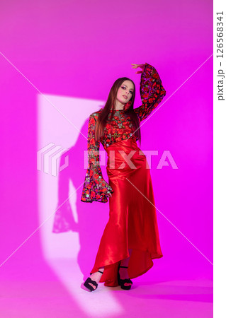 A Stunning Fashion Model Posing in a Colorful Dress Against a Vibrant Pink Background A Stunning Fashion Model Posing in a Colorful Dress Against a Vibrant Pink Background 126568341