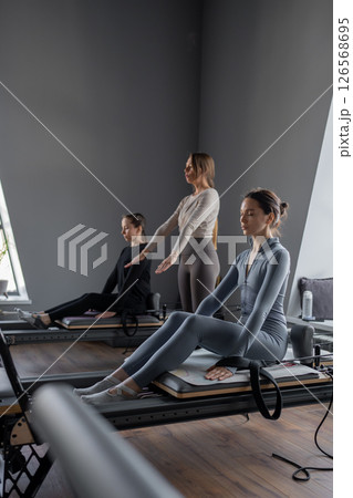 Woman training pilates on the reformer bed. Reformer pilates studio machine for fitness workouts in gym. Fit, healthy and strong authentical body. Fitness concept 126568695