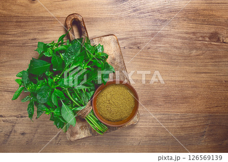 ground green basil, in a ceramic bowl, with a bouquet of fresh green basil, on the table, top view, no people, ground green basil, in a ceramic bowl, with a bouquet of fresh green basil, on the table, top view, no people, 126569139