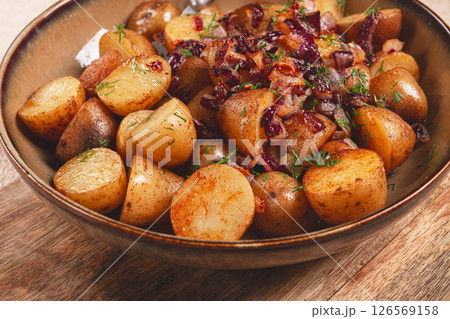 Deliciously roasted potatoes topped with savory onions and herbs on a wooden table 126569158