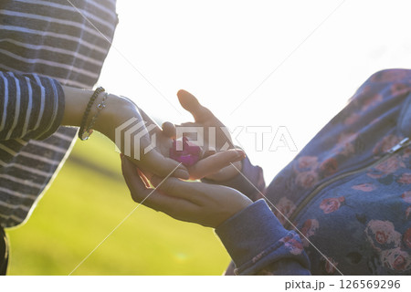 Two female friends one giving a beautiful purple blossom to another 126569296