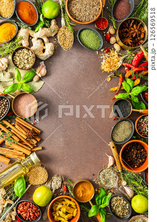 A colorful assortment of fragrant herbs and spices on a warm brown background, showcasing their visual variety and aromatic appeal, spice frame 126569518
