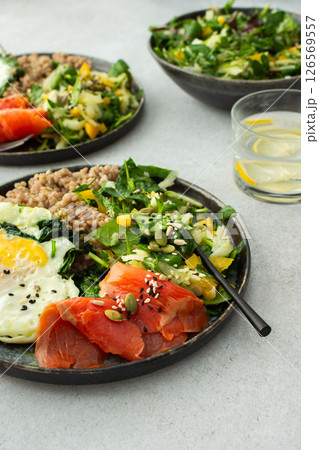 Buckwheat with fried egg and salmon fish, mix salad with fresh herbs and peppers 126569557