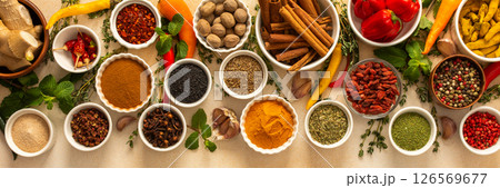 Variety of vibrant spices and dried herbs arranged on a beige backdrop, essential for culinary seasoning and enriching dishes with aromatic, natural flavors, banner 126569677
