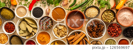 Collection of assorted spices and herbs spread on a beige background, blending exotic aromas and colors to inspire flavorful cooking, banner 126569697