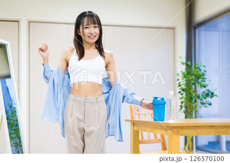 服を脱ぎ捨て、着替えてジムに向かう私服の若い女性　ヨガ　ストレッチ　ダイエット　健康 126570100