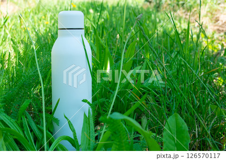 White thermo stainless bottle with refreshing water on the nature. 126570117