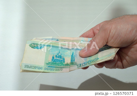 Hand holding a bunch of 1000-ruble bills. Symbol of salary, expenses, income. Hand holding a bunch of 1000-ruble bills. Symbol of salary, expenses, income. 126570371