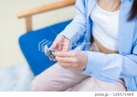 市販のワイヤレスイヤホンを手に取る女性の手 126571469