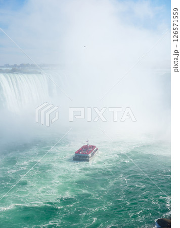 Niagara Falls. A pleasure boat with people near the huge famous waterfall. 126571559