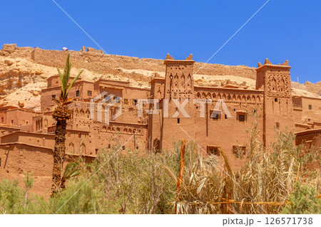 Ait Benhaddou ksar village walls and castle kasbah towers, with oasis in the foreground, Ouarzazate province, Morocco 126571738