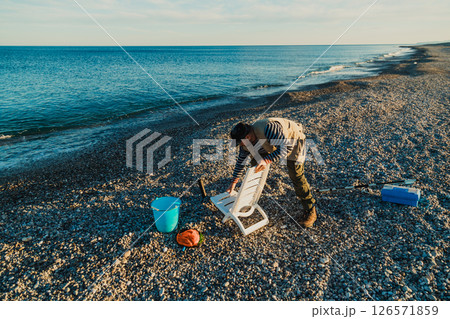Fisherman Preparing The Chair For A Day At The Sea  126571859