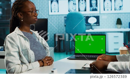 Doctor and patient discuss about health care recovery next to mockup screen, meeting in cabinet to share advice and medicine. Professional medic consulting girl during routine checkup. Camera A. Doctor and patient discuss about health care recovery next to mockup screen, meeting in cabinet to share advice and medicine. Professional medic consulting girl during routine checkup. Camera A. 126572389