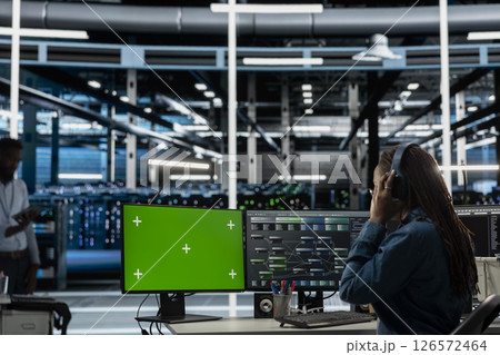 Servers room employee wearing audio headset doing maintenance using mockup PC. Technician in data center using green screen computer to check equipment performance, listening music 126572464