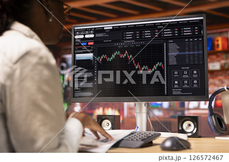 Day trader in home office purchasing stocks performing well, selling to gain money using PC display. Close up of woman browsing though stock exchange portfolio shares on computer screen 126572467