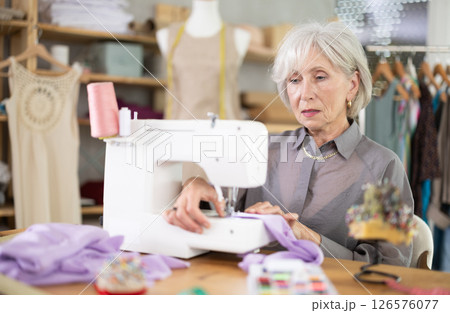 woman dressmaker sews on a machine in a workshop woman dressmaker sews on a machine in a workshop 126576077
