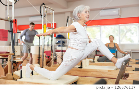 Elderly woman doing stretching on pilates machine 126576117