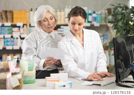Woman pharmacist at computer communicate with senior female client 126576138