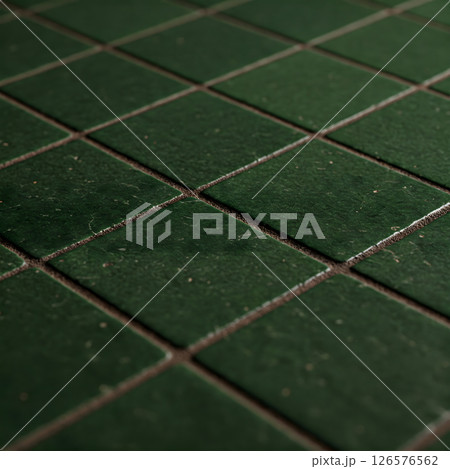 Dark green square tiles laid diagonally with dark grout lines create a textured surface 126576562