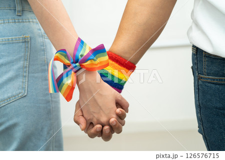 Asian LGBT couple woman holding hand wearing rainbow wristband. 126576715