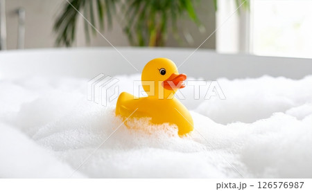 A fun yellow plastic rubber duck toy floats in the baby's bathwater A fun yellow plastic rubber duck toy floats in the baby's bathwater 126576987