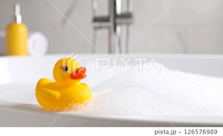 A fun yellow plastic rubber duck toy floats in the baby's bathwater 126576989