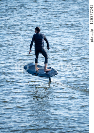 Surfer rides electric hydrofoil board above choppy water Surfer rides electric hydrofoil board above choppy water 126577243