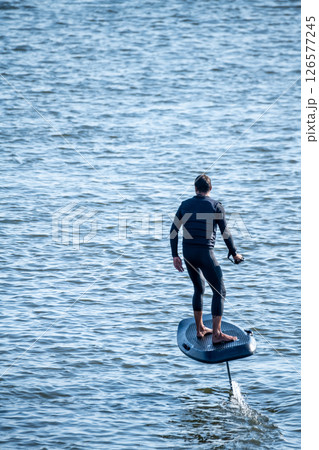 Hydrofoiling on a calm blue sea Hydrofoiling on a calm blue sea 126577245