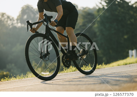 Woman cycling on summer park trail Woman cycling on summer park trail 126577370