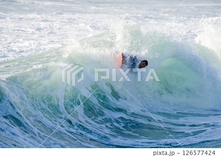 Bodyboarder surfing ocean wave 126577424