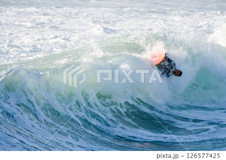 Bodyboarder surfing ocean wave 126577425