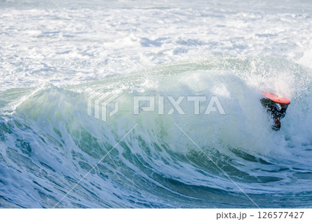 Bodyboarder surfing ocean wave 126577427