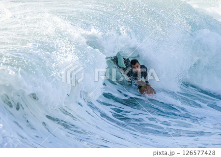 Bodyboarder surfing ocean wave 126577428