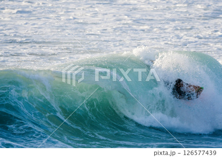 Bodyboarder surfing ocean wave 126577439