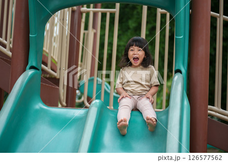 happy toddler baby girl sliding and playing at playground 126577562