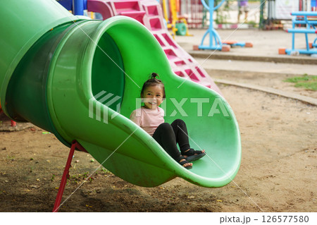 happy toddler baby girl sliding and playing at playground 126577580