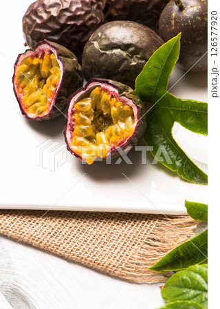 Passion fruits on white ceramic tray on wooden table background. Passion fruits on white ceramic tray on wooden table background. 126577920